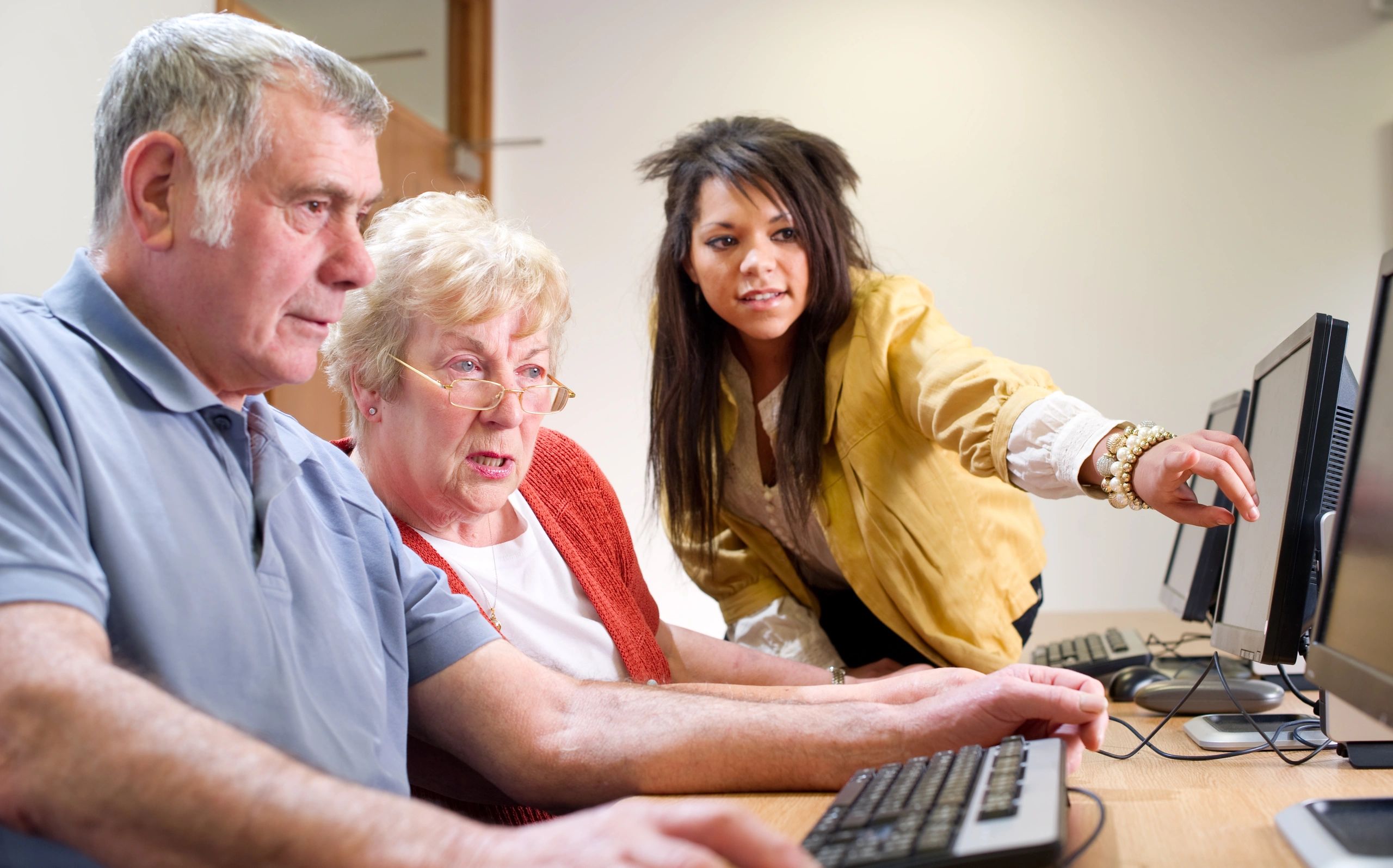 Personas mayores recibiendo ayuda en una clase de computación