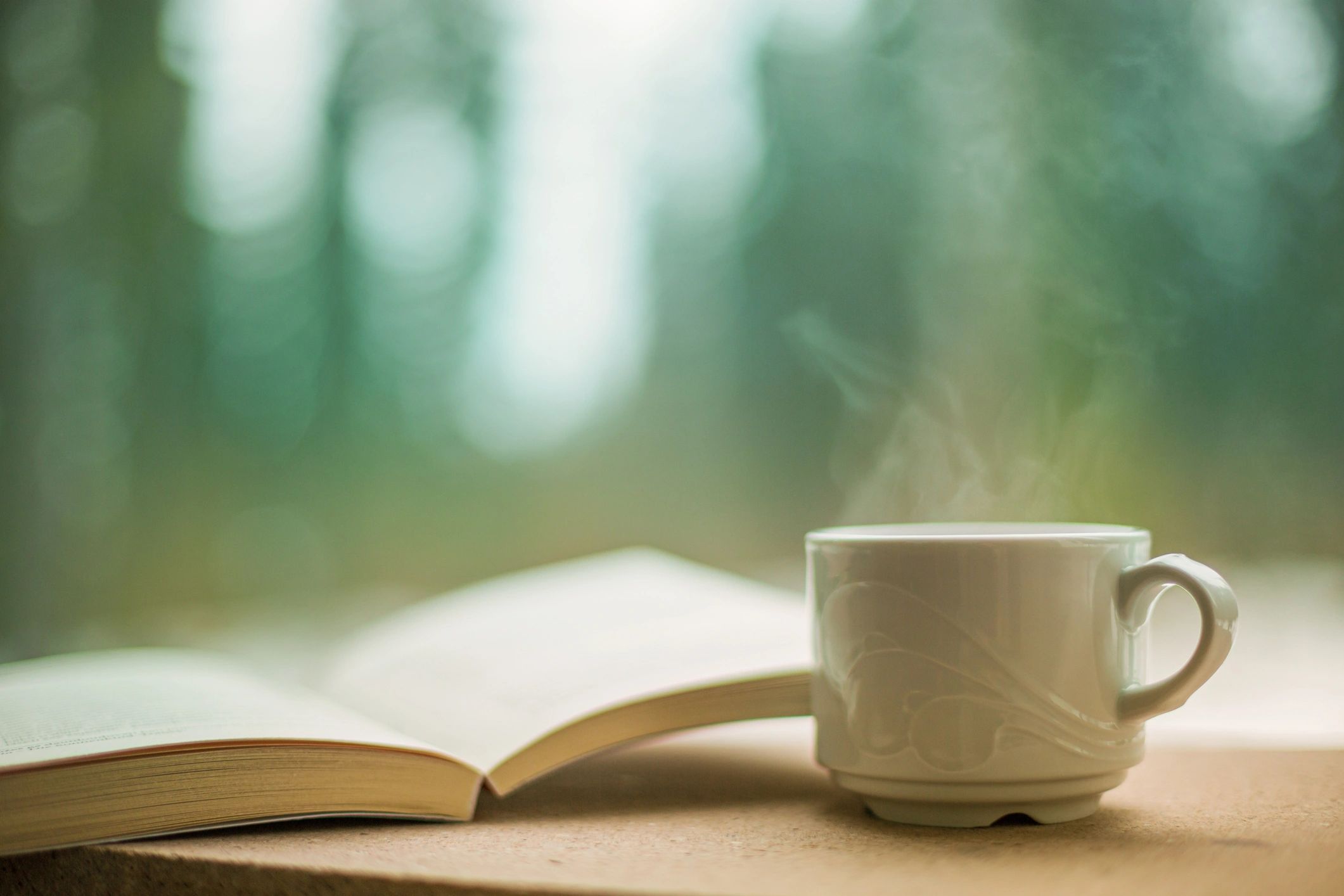 Libro abierto junto a una taza de café, ambiente de lectura