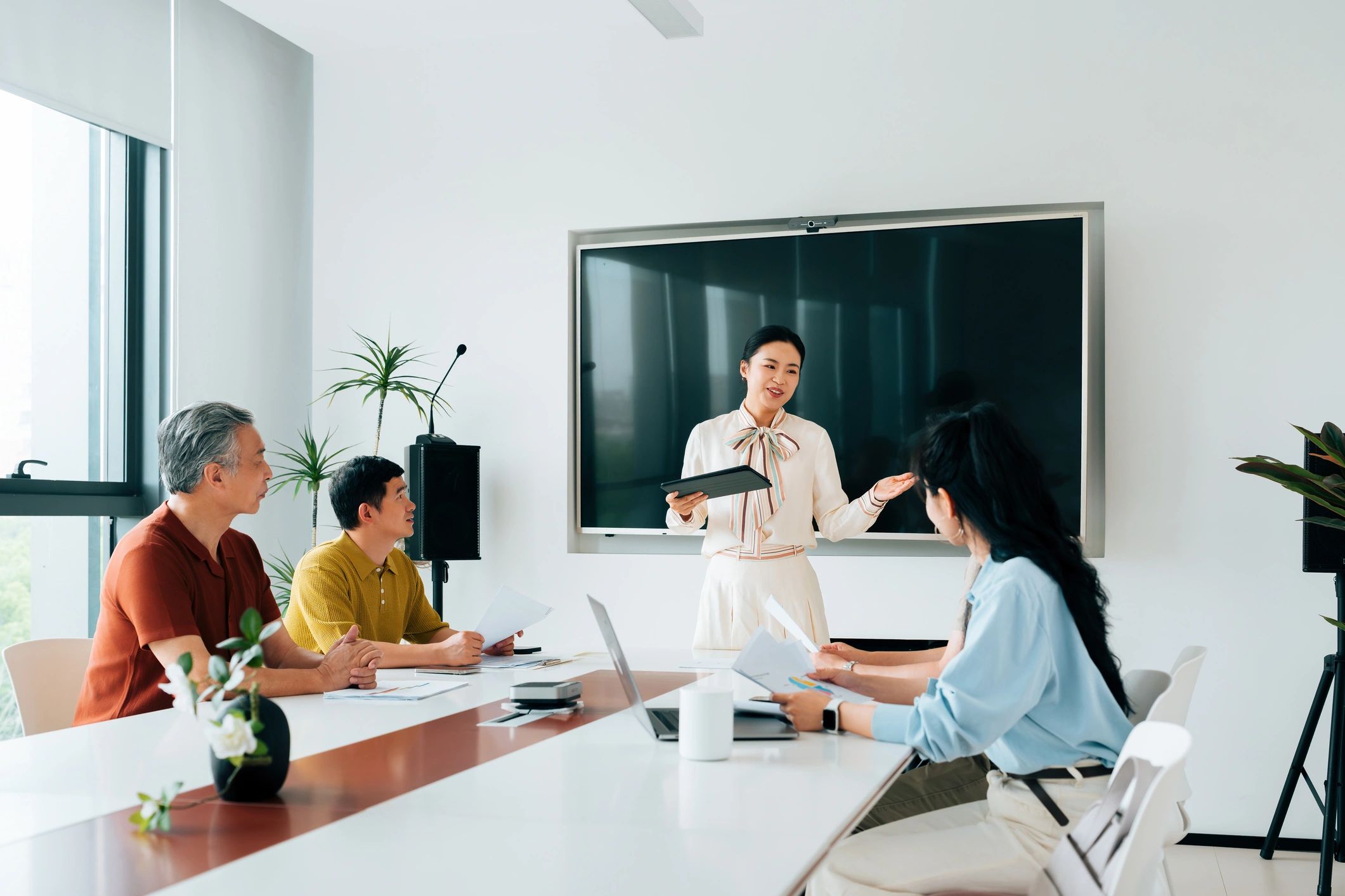 Facilitadora presentando una charla a un grupo intergeneracional en una sala de reuniones