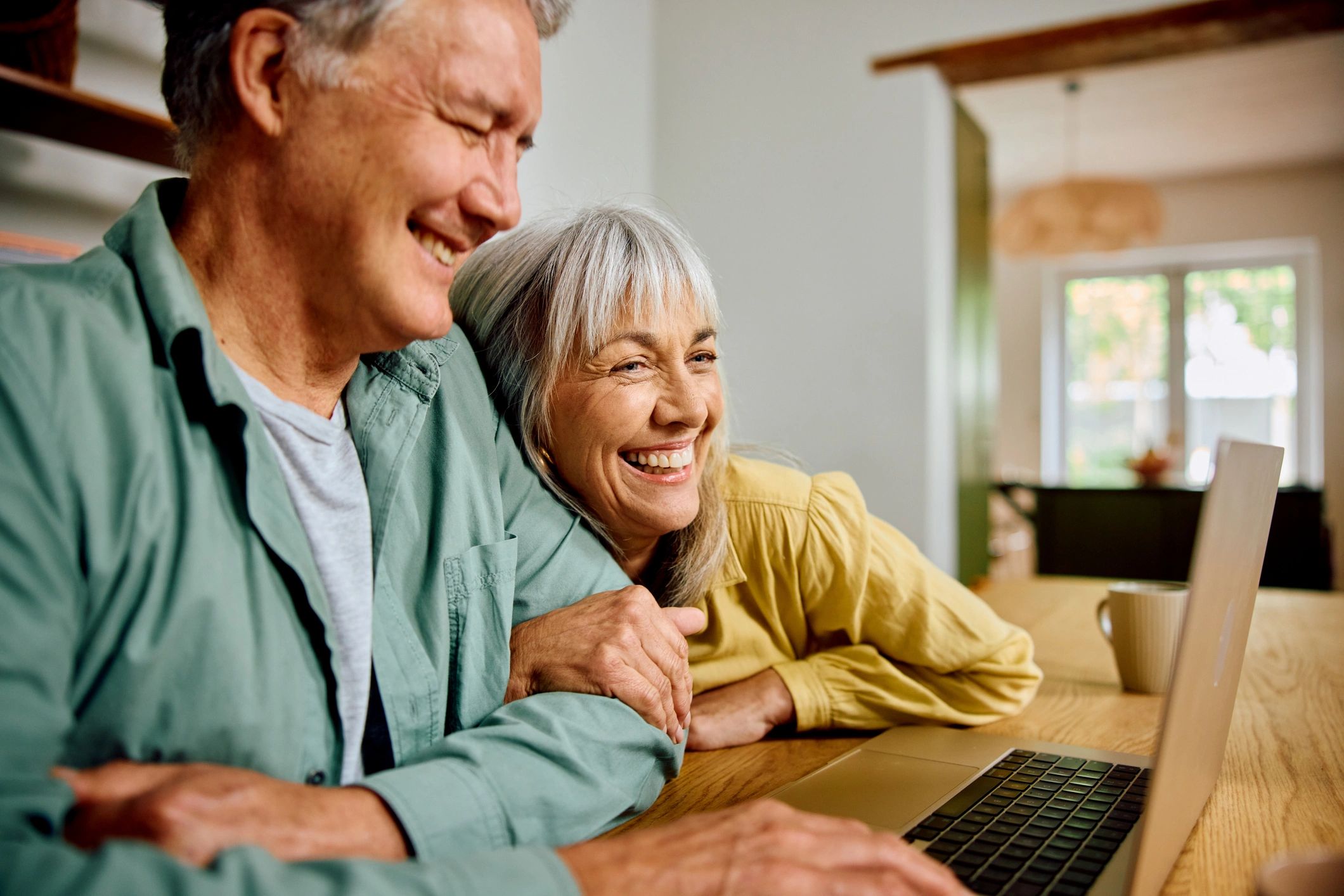 Pareja de adultos mayores usando una laptop con tranquilidad
