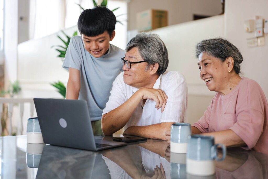 A young Chinese boy is teaching his grandfather new computer technology. The elderly grandparent is learning to use a computer at home.